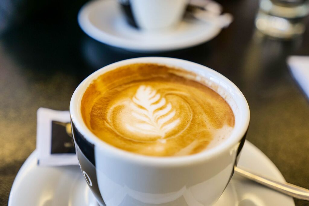 Aesthetic close-up of a cappuccino cup showcasing intricate latte art on a table.
